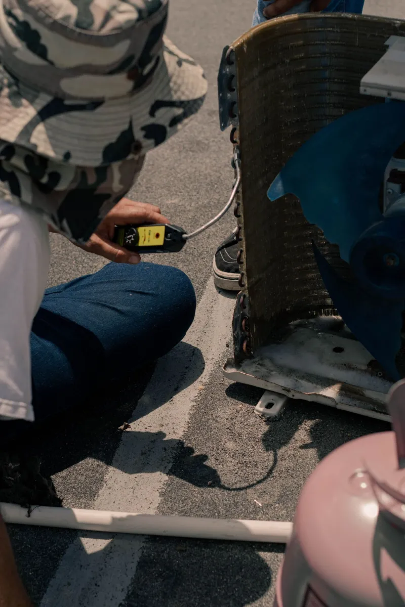 AC technician testing an air conditioner with a multimeter